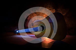 Music concept. Acoustic guitar isolated on a dark background under beam of light with smoke with copy space. Guitar Strings, close