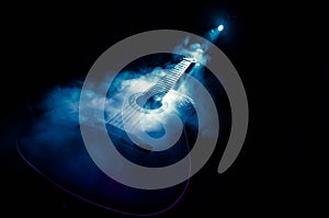 Music concept. Acoustic guitar isolated on a dark background under beam of light with smoke with copy space. Guitar Strings, close