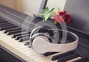 Music and  concept.Music headphone on piano keyboard with red rose.vintage filtered,selective focus