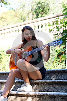 Music Concept: Young and Beautiful woman playing Spanish guitar outdoors in a park