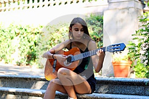 Music Concept: Young and Beautiful woman playing Spanish guitar outdoors in a park