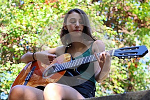 Music Concept: Young and Beautiful woman playing Spanish guitar outdoors in a park