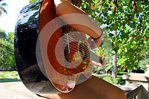 Music Concept: Young and Beautiful woman playing Spanish guitar outdoors in a park