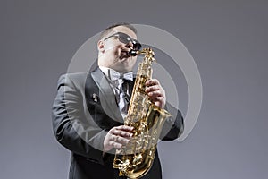 Music Concepts. Portrait of Mature Expressive Caucasian Saxophone Player in Sunglasses Playing the Saxophone in Studio