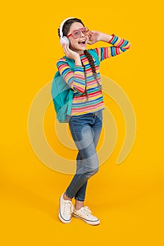 Music education. Teen girl singing along to music after school yellow background, music