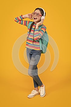 Music education. Teen girl singing along to music after school yellow background, music