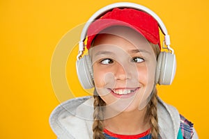 Music with emotions. Squint-eyed kid on yellow background. Funny child listen to music in stereo headphones. Small child