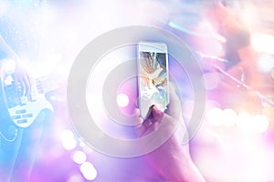 Music fans takes a photo guitarist on stage in concert on smart phone, Soft focus and pastel color tone