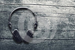 Music grunge background, black headphones on a wooden table