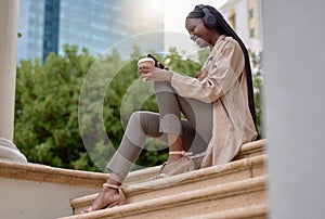 Music headphones, phone and black woman with coffee while sitting on city steps. Technology, tea break and happy female