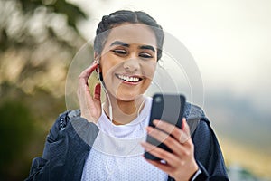 Music helps distract the brain from your bodys exertion. a sporty young woman wearing earphones and using a cellphone