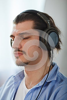 Music in his mind. Portrait of young man wearing headphones and closed eyes