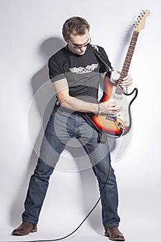 Music Ideas and Concepts. Male Guitar Player Posing With Guitar Expressively Against White.
