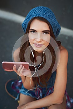 Music is important to her. Portrait of a carefree young woman seated on the floor while listening to music through her