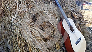 Music instrument guitar leaning on the haystack