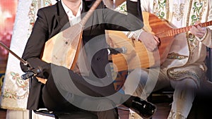 Music of Kazakhstan. Male musicians play the dombra. Kazakh national musical instruments and clothing. Concert performance.