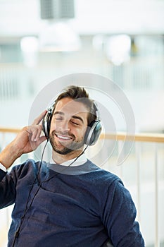 Music keeps me motivated for the day. Shot of a young businessman listening to music in an office.