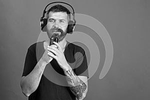 Music and leisure concept. Singer with beard and admired face listens to music. Dj with beard wears headphones, copy