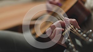 Music lesson. Man playing melody by acoustic guitar, practicing chords on stringed instrument, close-up. ProRes codec