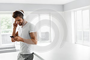 Music Listening. Man In Headphones Using Mobile Phone Indoors