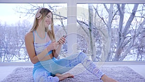 Music lover in headphones listens to melodies and dances sitting near window at home