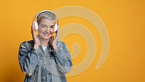 Music lover. Portrait of smiling mature woman in wireless headphones