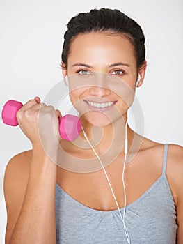 Music makes her workout easier. Portrait of a young woman working out with weights while listening to music.