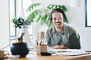 Music makes life bearable. a young businessman wearing headphones in an office.