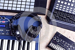 Music making equipment with keyboards, controllers and headphones on wooden background, top view