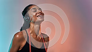 Music making me happy. Side view of smiling young woman in headphones holding jumping rope on shoulders and keeping eyes