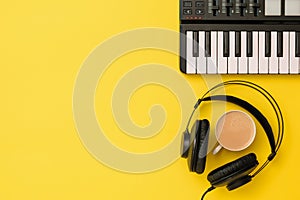 Music mixer and black headphones and coffee on yellow background. The view from the top