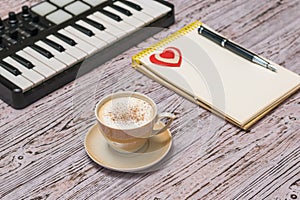 A music mixer, a Cup of coffee and a notebook on a wooden table.