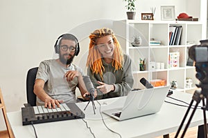 Music is our life. Man and woman making music using synthesizer, drum pad machine. Female and male bloggers recording