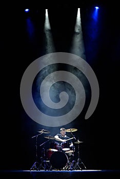 music, people, musical instruments and entertainment concept - male musician with drumsticks playing drums on the stage