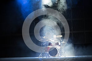 music, people, musical instruments and entertainment concept - male musician with drumsticks playing drums on the stage