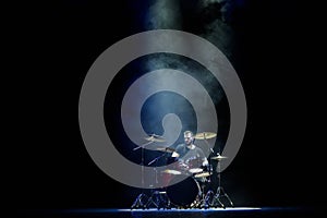 music, people, musical instruments and entertainment concept - male musician with drumsticks playing drums on the stage