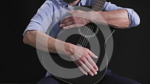 music performer, a man with a guitar in his hands beats rhythm on dark background