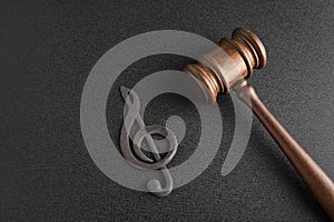 Music piracy concept. Treble clef next to gavel on black background. Music copyrights