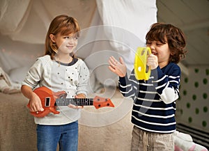 Music, playing and children with instruments in bedroom for fun, bonding and band practice. Happy, smile and young girl