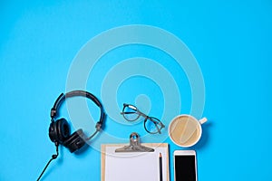 Music or podcast background with headphones, microphone, coffee and blank on blue table, flat lay. Top view, flat lay