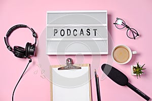 Music or podcast background with headphones, microphone, coffee and blank on pink table, flat lay. Top view, flat lay