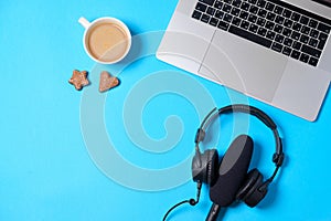 Music or podcast background with headphones, microphone, coffee and laptop on blue table, flat lay. Top view, flat lay