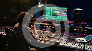 Music producer editing sounds with mixing console and switchers