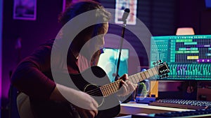 Music producer tuning his acoustic guitar before playing instrument,