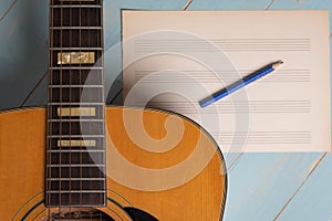 Music recording scene with guitar, empty music sheet and pencil