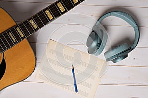 Music recording scene with guitar, empty music sheet, pencil and headphones
