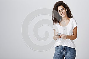 Music saves memories of lifetime. Portrait of good-looking positive european woman in stylish glasses holding smartphone
