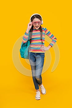 Music school. Teen girl singing along to music after school yellow background, music