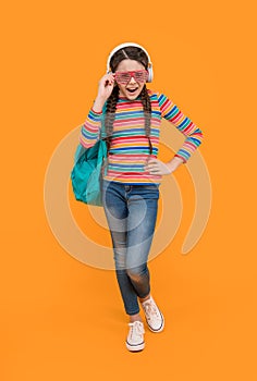 Music school. Teen girl singing along to music after school yellow background, music