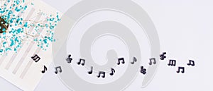 Music sheet, black musical notes and dried flowers on a light background top view web banner